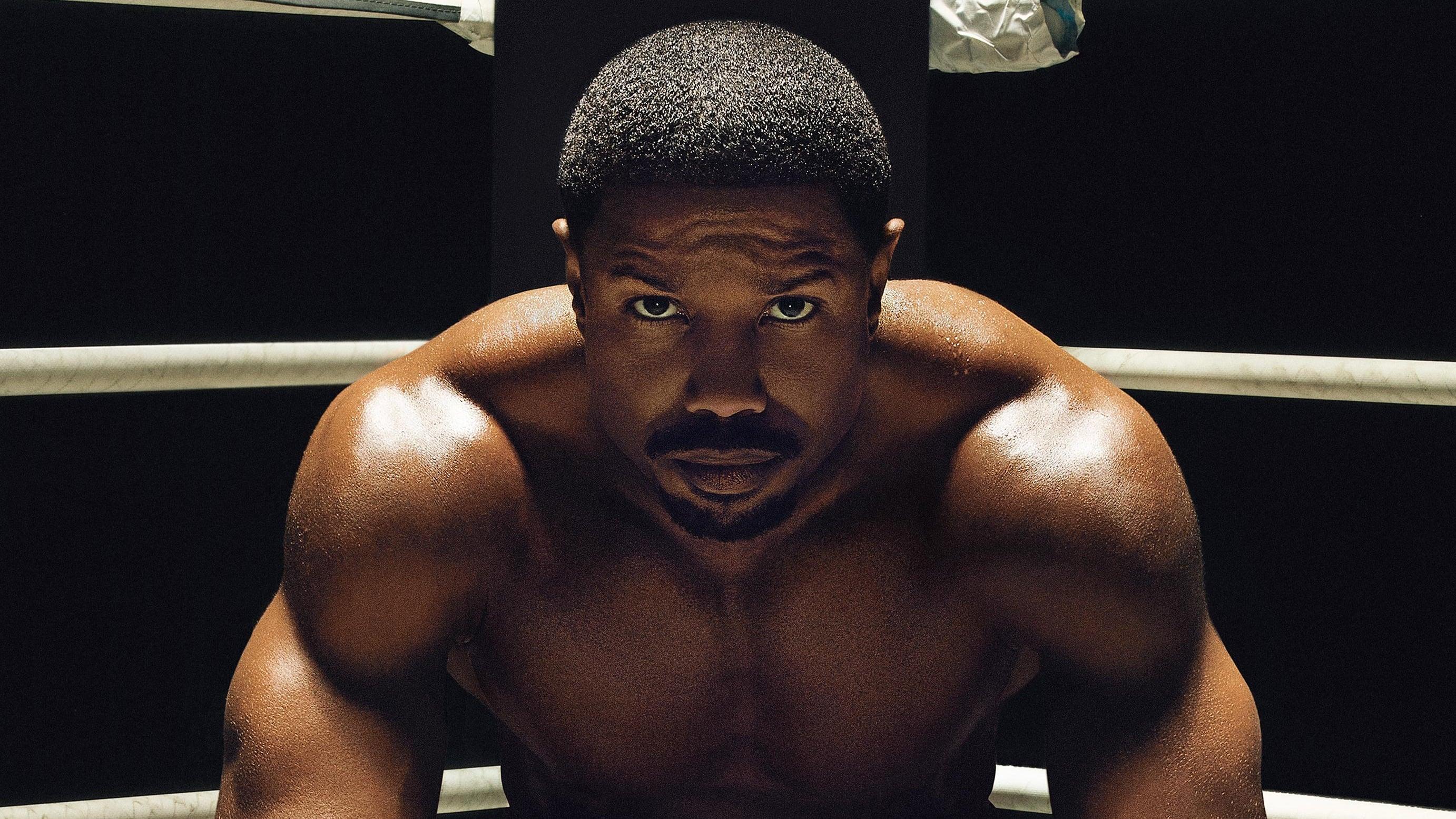 Michael B. Jordan sits hunched over in the corner of a boxing ring in this still from Creed III.